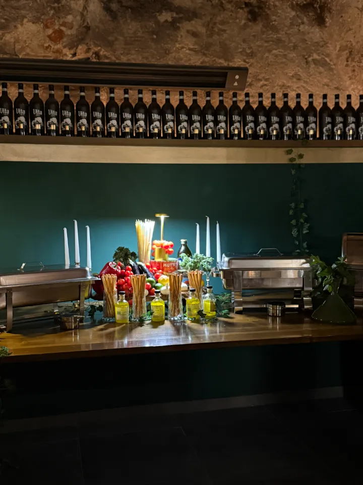 Buffetstation vor petrolgrüner Wand mit Flaschenregal