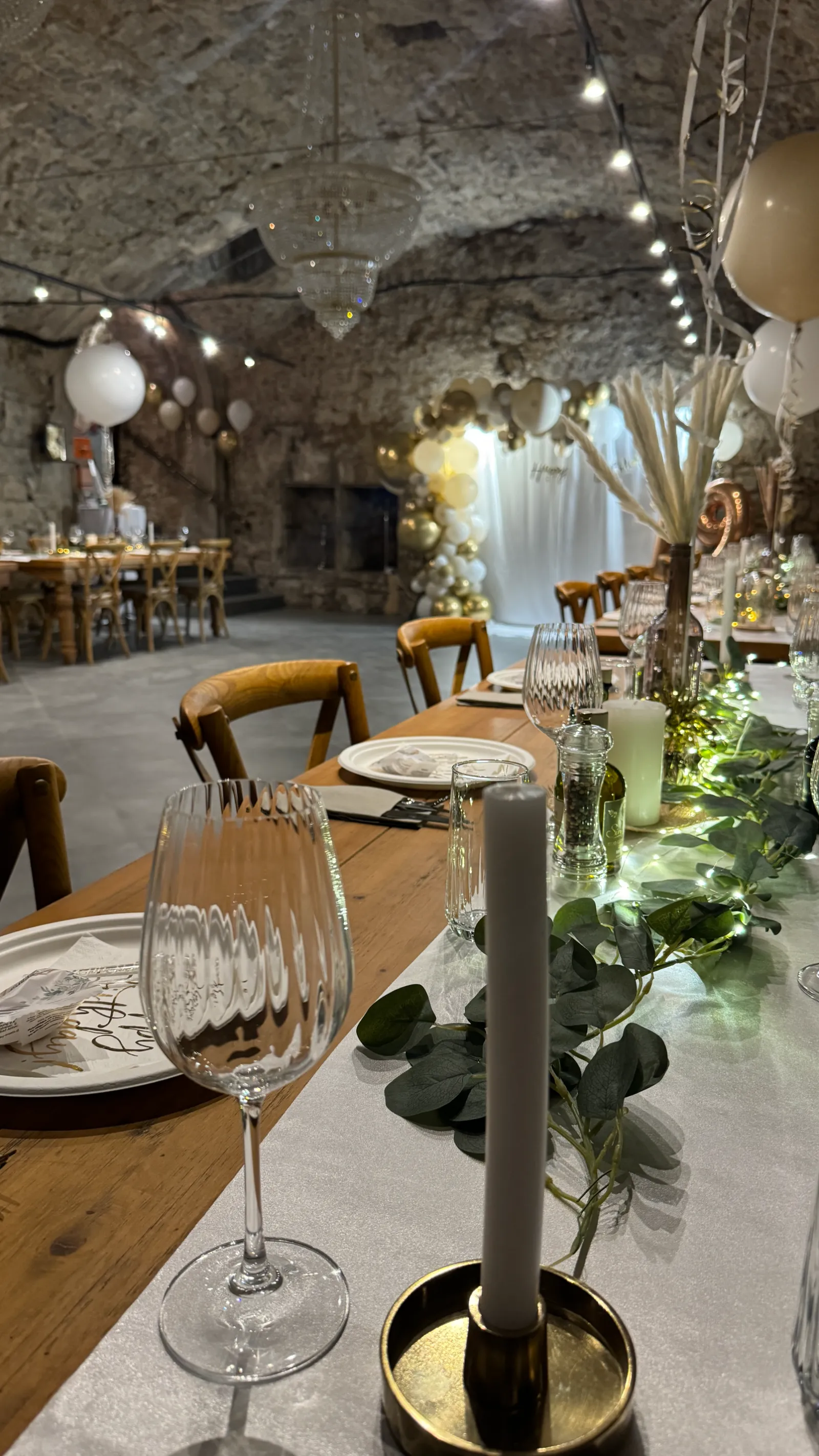 Tisch mit Kerze, Eukalyptus und einem Ballonbogen im Hintergrund