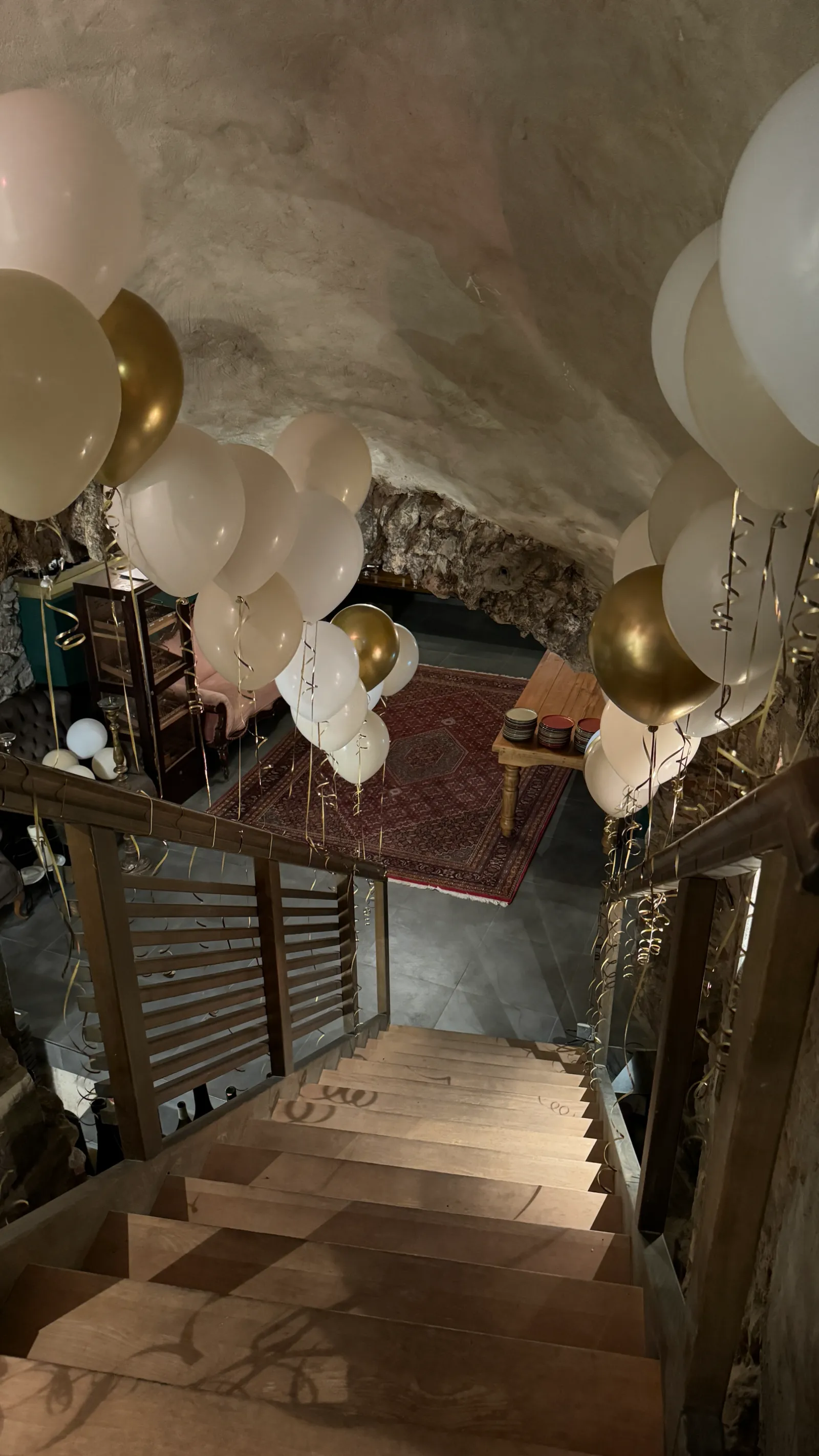 Treppe hinab in den Keller, gesäumt von weißen und goldenen Ballons